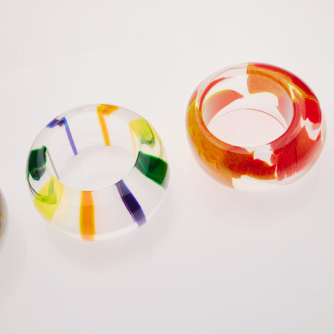Four acrylic bracelets lined up on a diagonal.